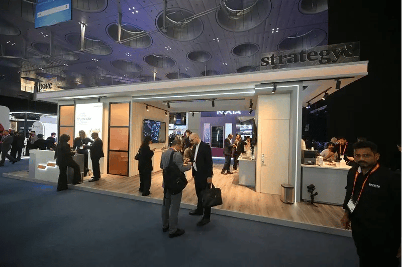 Attendees networking and engaging with representatives at the PwC and Strategy& stand during MWC Doha, exploring business growth and technology transformation solutions.