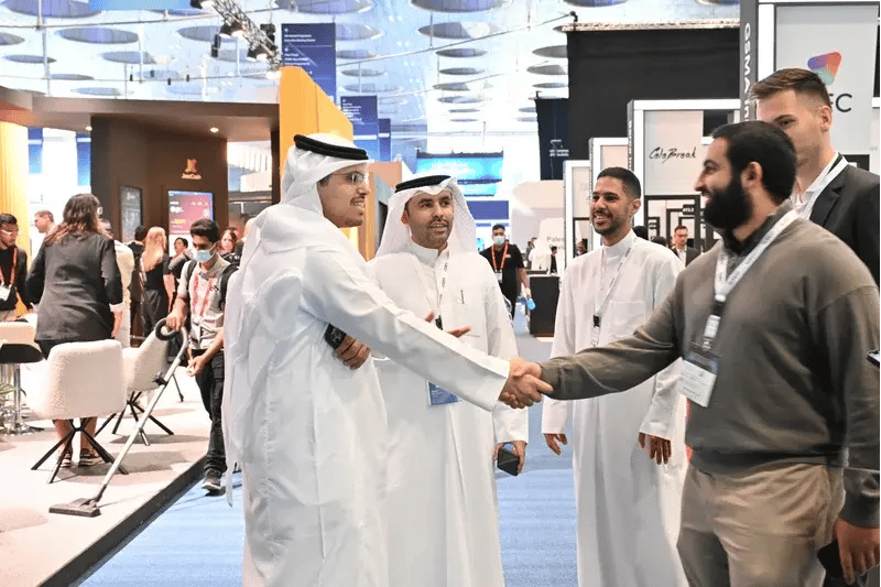 Attendees greet one another with a handshake while networking on the MWC exhibition floor, highlighting business collaboration and industry connections at the event.